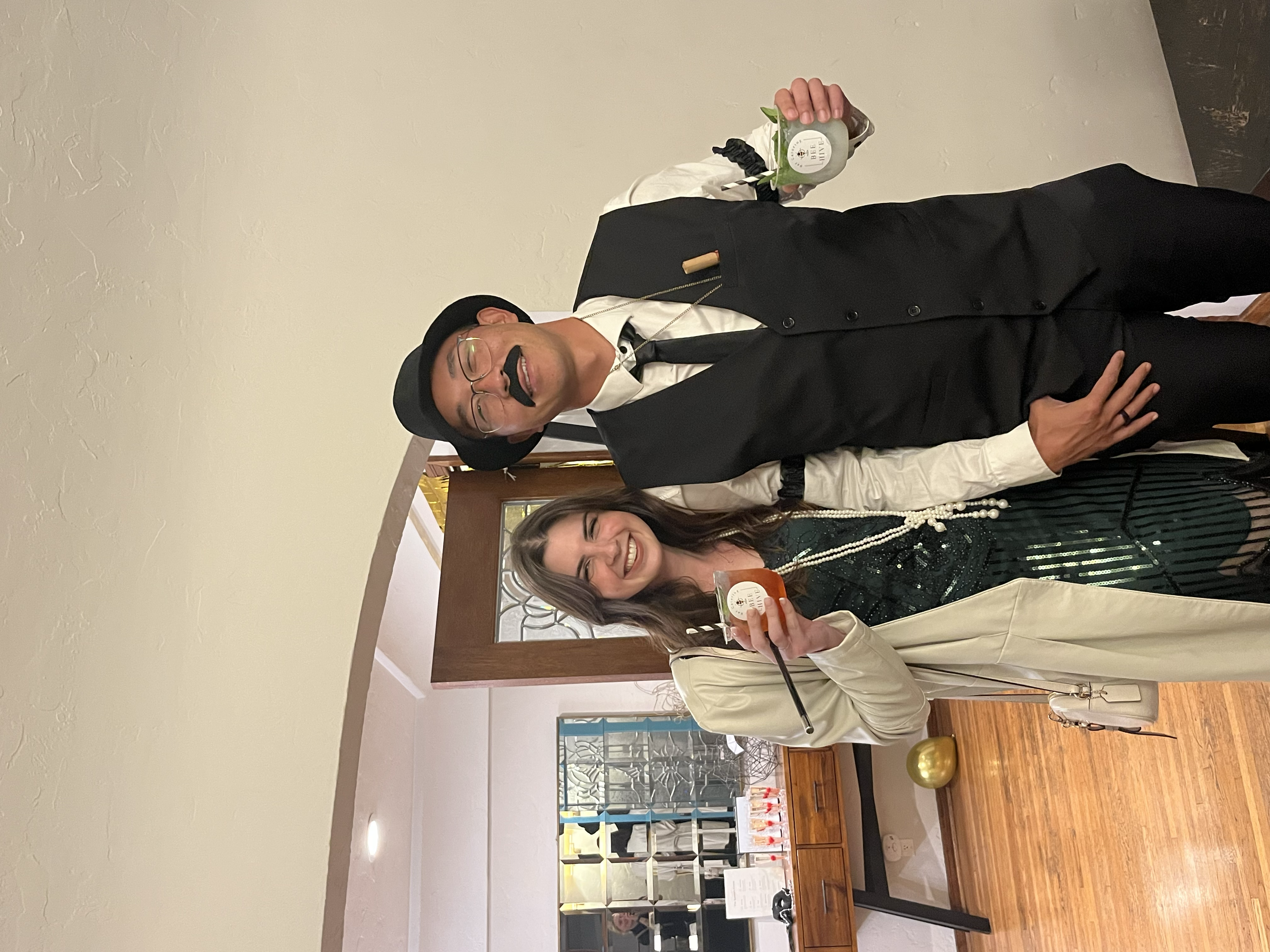 Two smiling guests holding BeeHive cocktails at a celebration